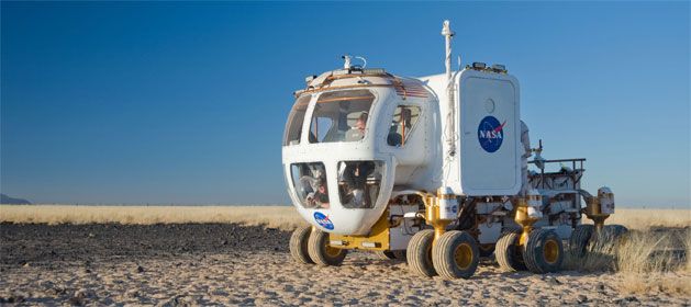 a vehicle that is sitting in the middle of some dirt and has wheels attached to it