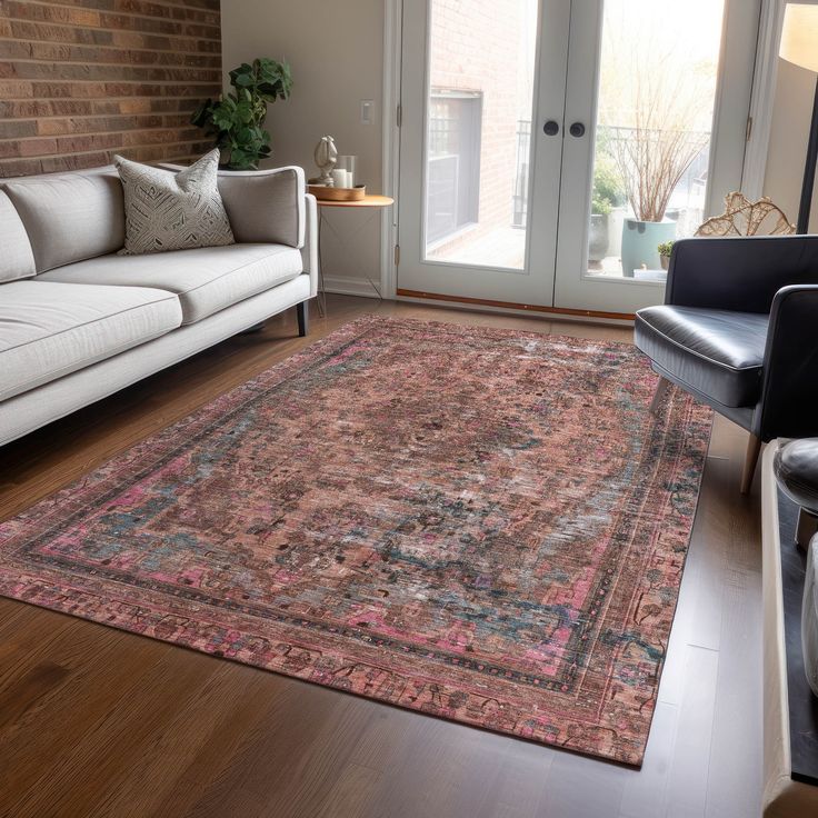 a living room filled with furniture and a rug on top of a hard wood floor