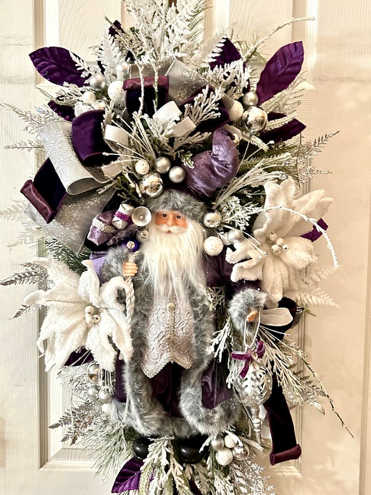 a christmas wreath with purple and white decorations hanging on a front door ornament