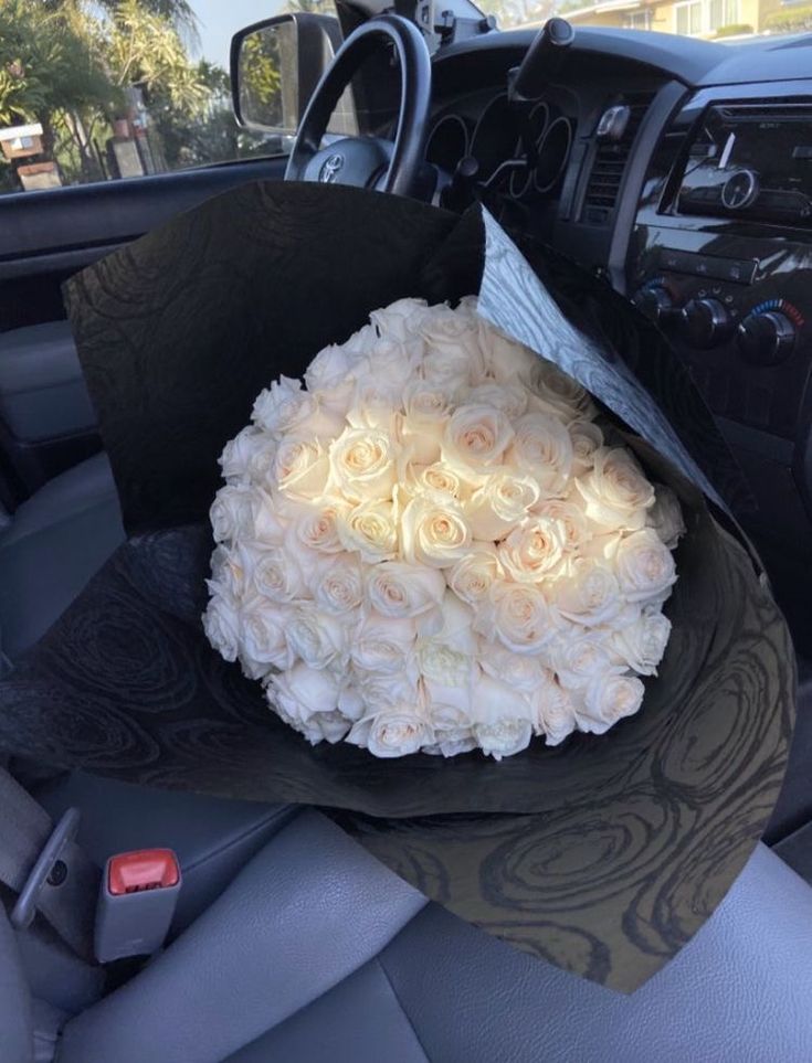 a bouquet of white roses is sitting in the back seat of a car, ready to be delivered