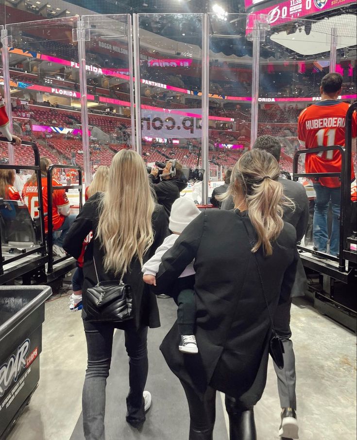 two women are walking towards the ice at a hockey game