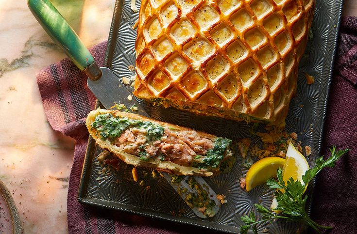 a waffle sandwich on a plate next to a knife and some lemon wedges