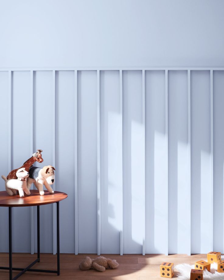 two small dogs sitting on top of a table in front of a wall with vertical blinds