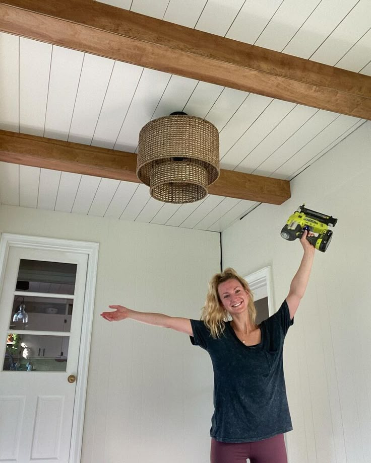 a woman is holding her arms up in the air while standing under a light fixture