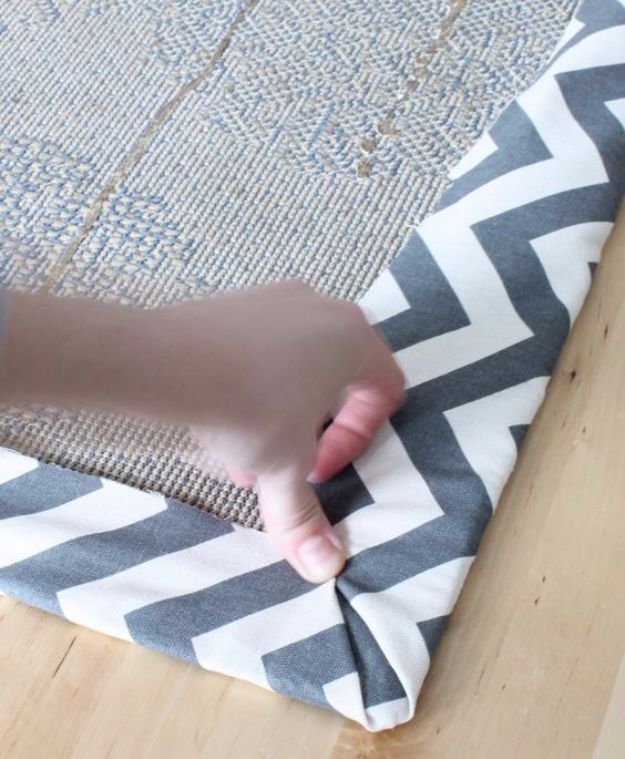 a person is touching the edge of a rug on top of a wooden floor with their hand