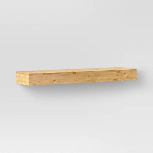 a wooden shelf sitting on top of a white wall