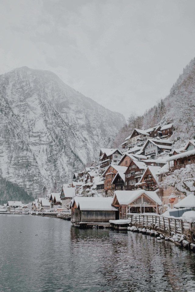 the snow covered mountains are in the background and houses on the water near them,