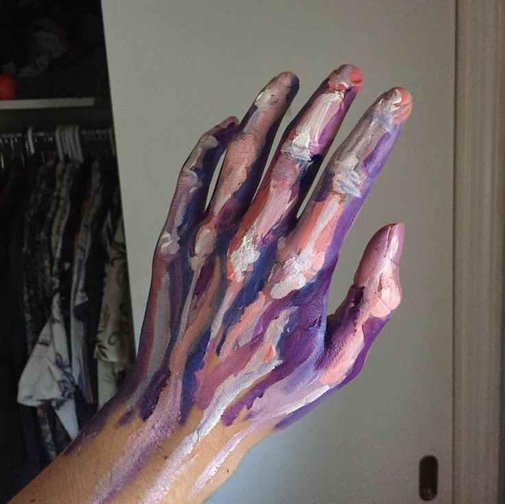 a person's hand covered in purple and pink paint