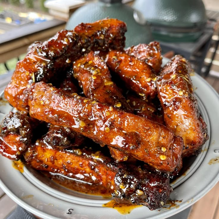 a white plate topped with chicken wings covered in bbq sauce and seasoning on top of a wooden table