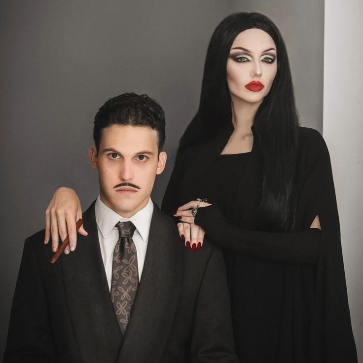 a man and woman dressed in black standing next to each other with makeup on their faces