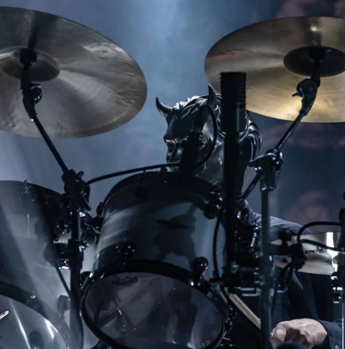 the drummer is playing drums on stage with his head in the drum kit and lighting behind him