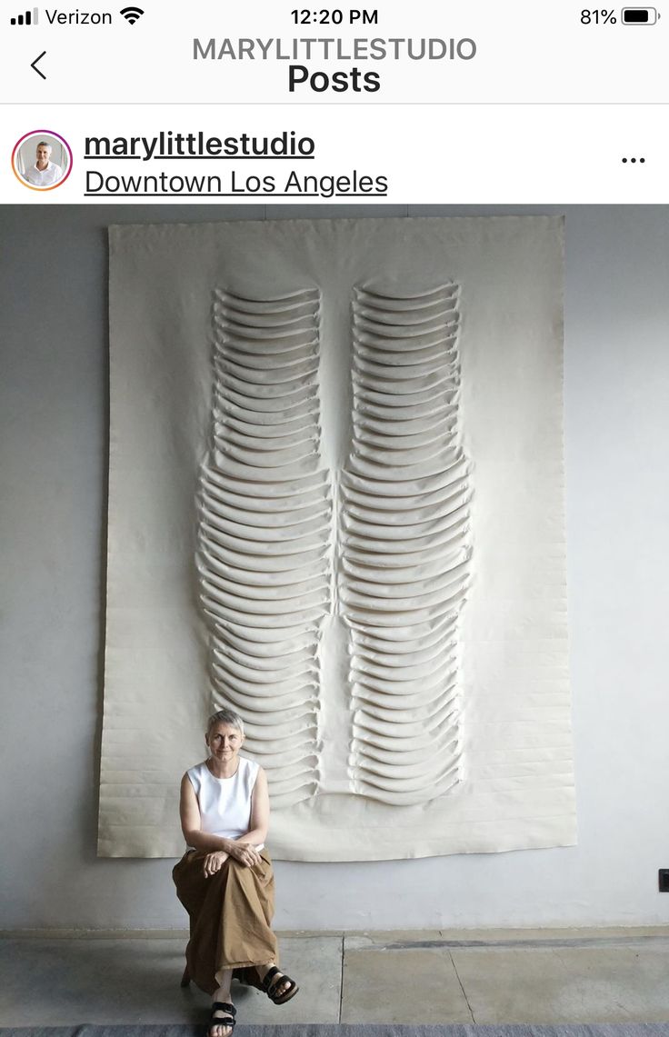 a woman sitting in front of a white sculpture