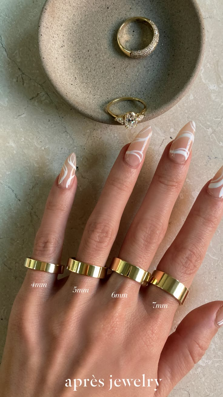 a woman's hand with two gold rings on it and a ring in the middle