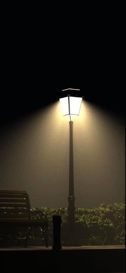 a bench sitting under a street light in the foggy dark night with no one on it