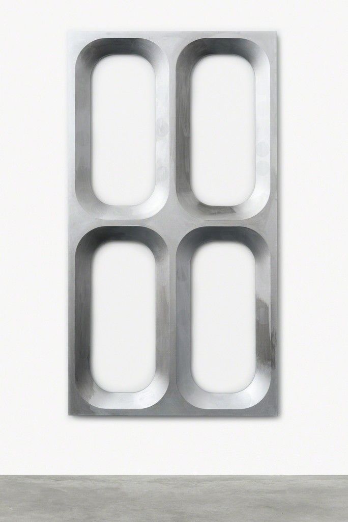 an abstract metal sculpture with four square holes in the center, on a white wall