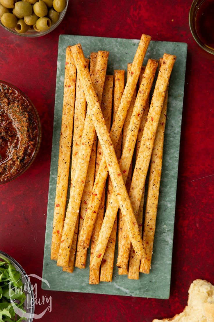 french fries on a plate with olives and breadcrumbs in the background