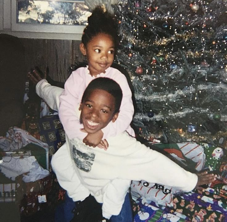 two children sitting in front of a christmas tree