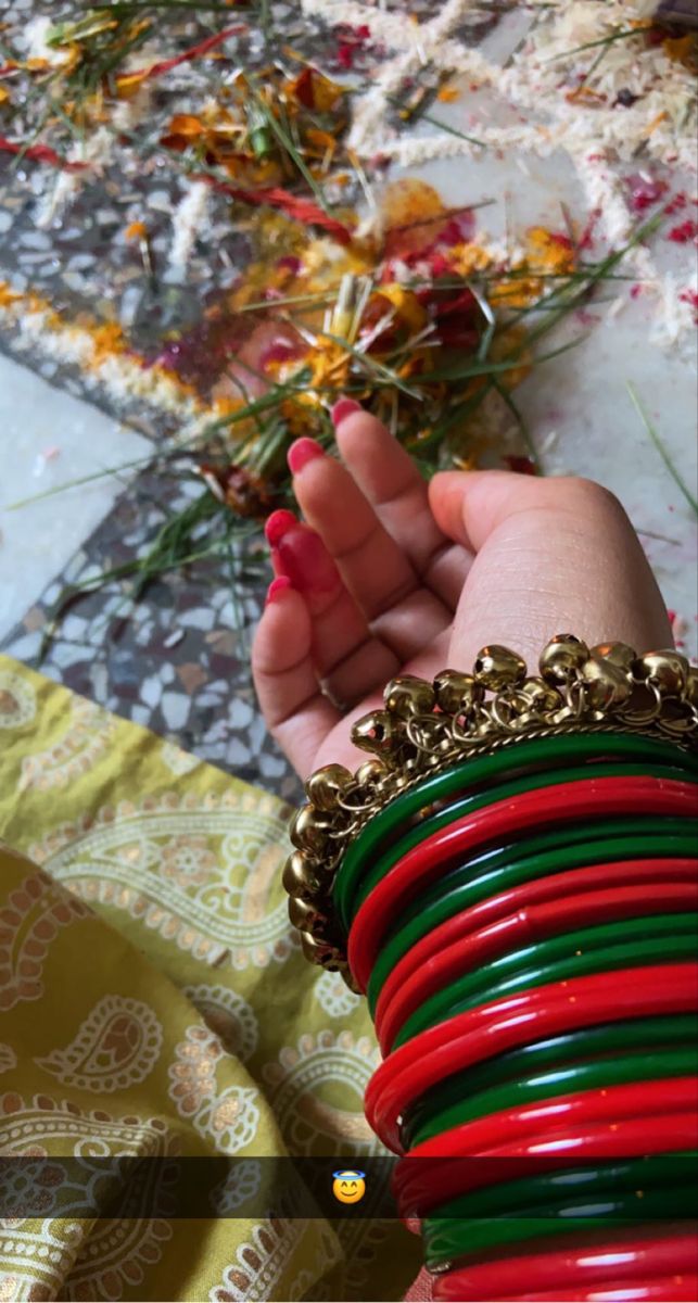 a hand holding several bracelets on top of a bed covered in colorful fabric and flowers