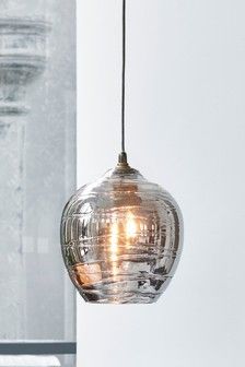 a glass light hanging from a ceiling in a room with white walls and flooring