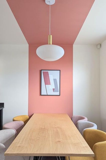 a dining room with pink walls and yellow chairs