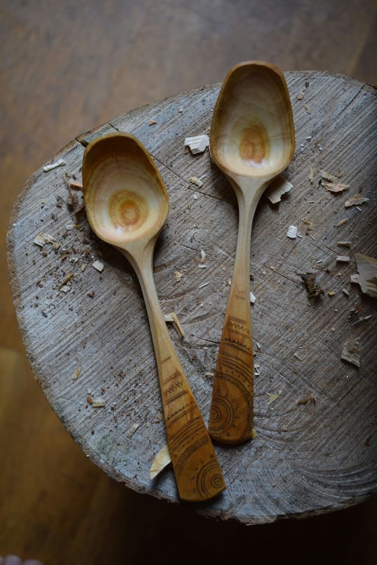 two wooden spoons sitting on top of a piece of wood