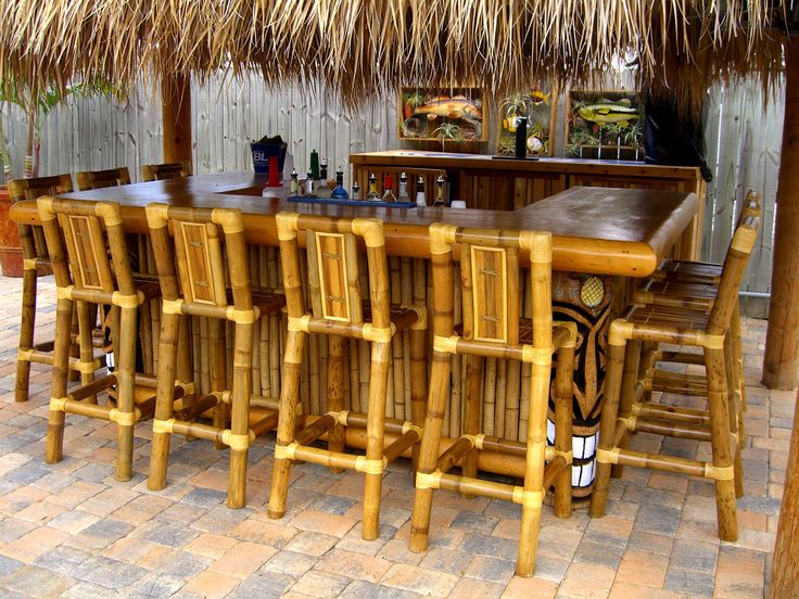 an outdoor bar with chairs and tables made out of bamboo straw thatched umbrellas