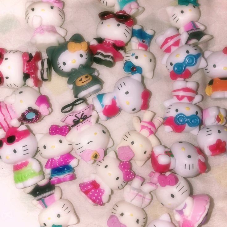 a bunch of hello kitty figurines sitting on top of a white tablecloth