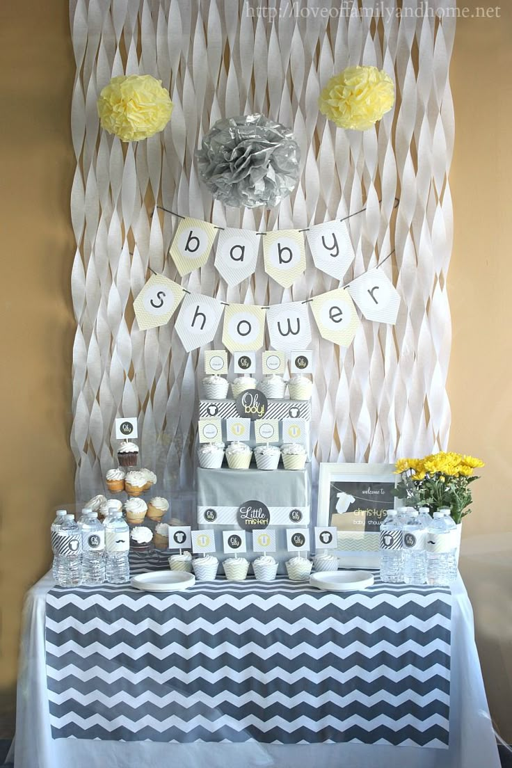 a baby shower party with blue, white and yellow decorations on the wall next to it