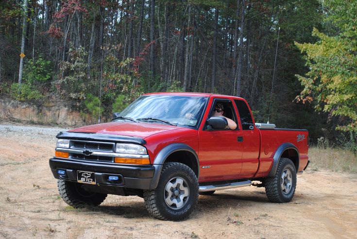 a red pick up truck parked in the dirt