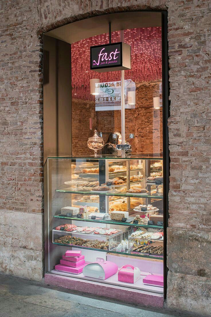 a bakery window with pastries and cakes in it's display case on the sidewalk