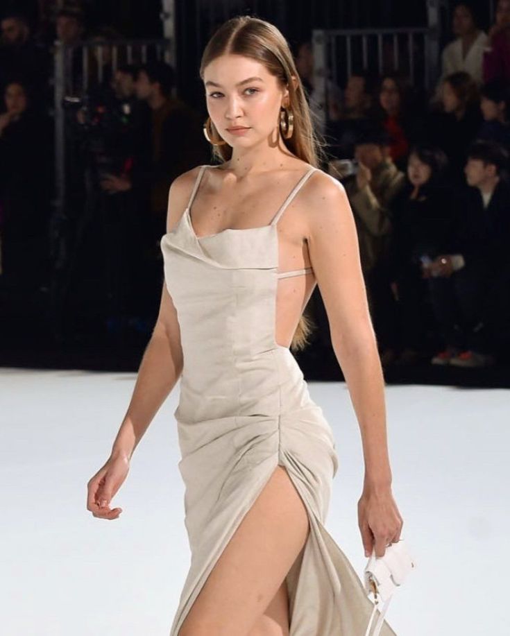 a woman walking down a runway wearing a dress with thigh high slits and heels