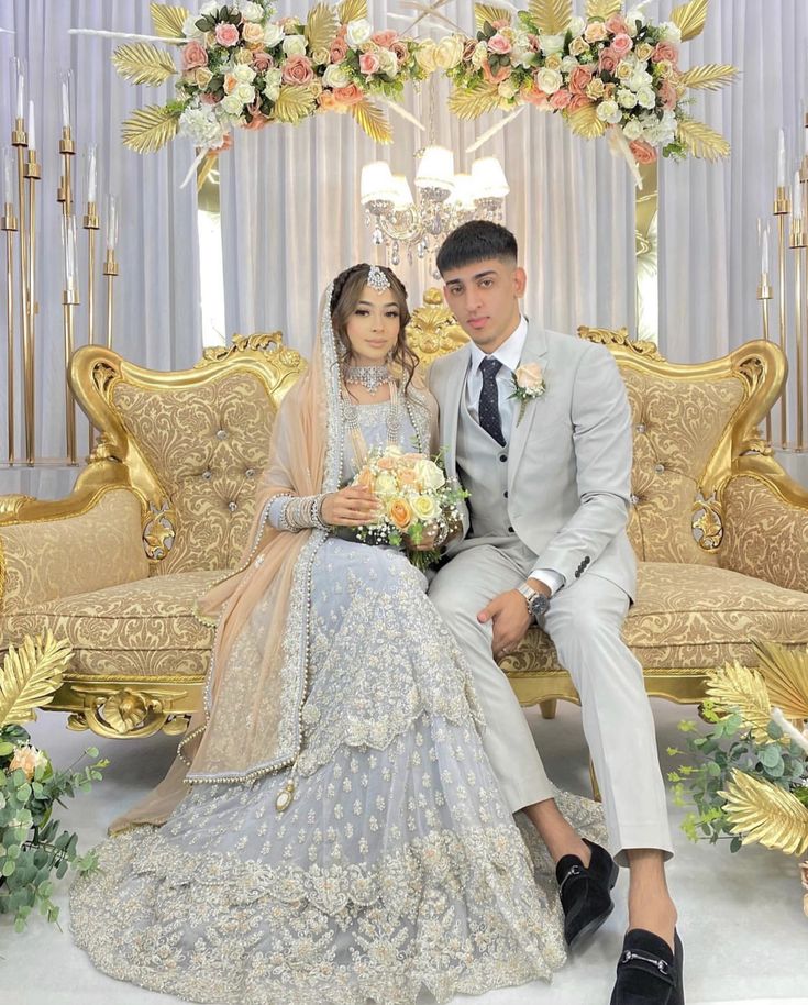 a bride and groom sitting on a gold couch