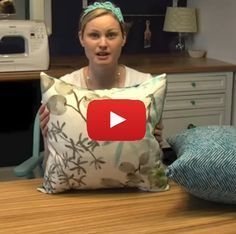 a woman sitting at a kitchen counter holding a pillow