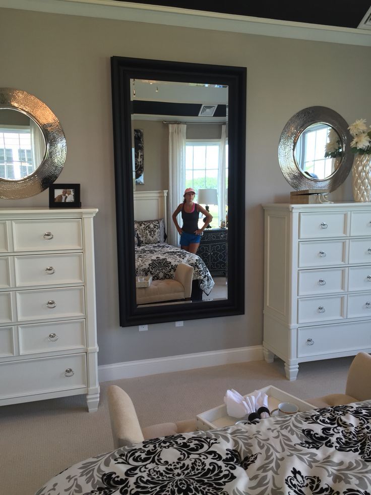 a woman taking a selfie in a mirror next to a bed and dressers