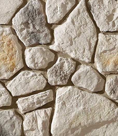 a stone wall that is made out of various types of rocks and has yellow paint on it