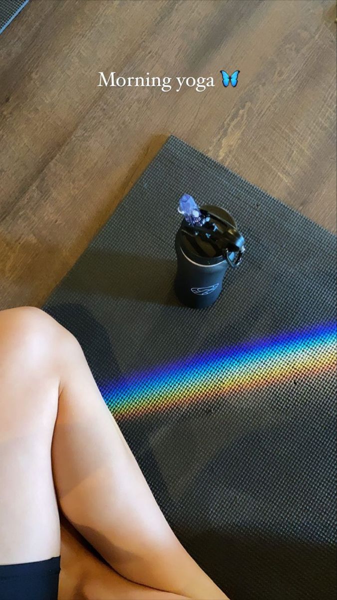 a woman sitting on top of a yoga mat next to a pot with a rainbow in it