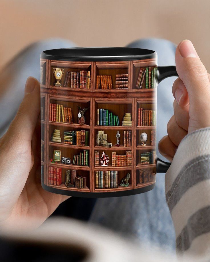 a person holding a coffee mug with bookshelves on the front and sides in their hands