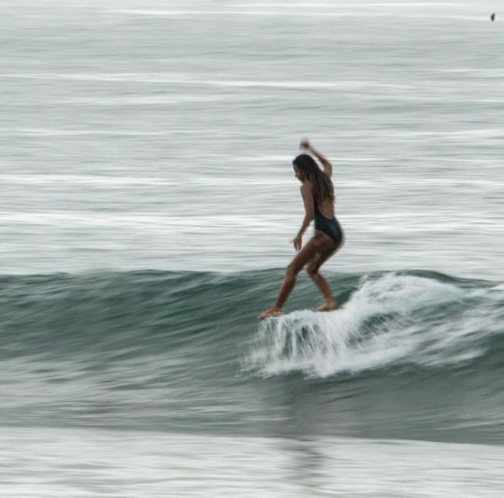 a woman riding a wave on top of a surfboard