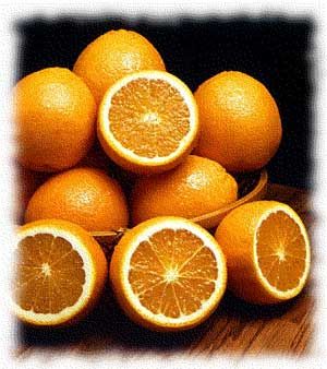 a bowl filled with lots of oranges on top of a wooden table next to a black background