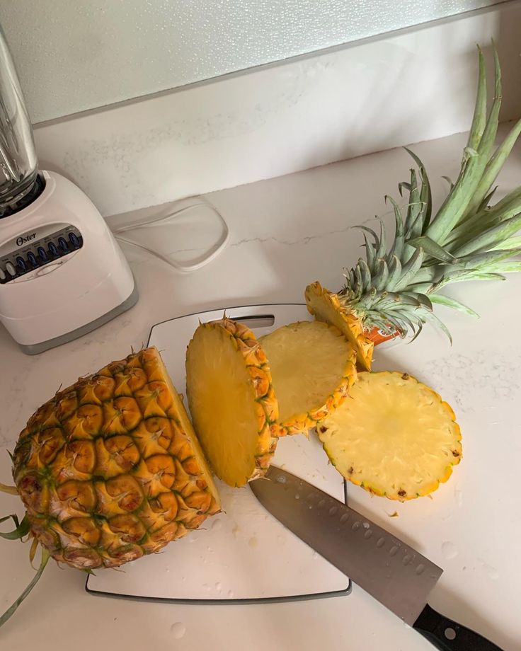 sliced pineapple on a cutting board next to a knife