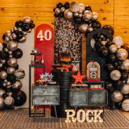 an assortment of black and silver balloons in front of a sign that says rock on it