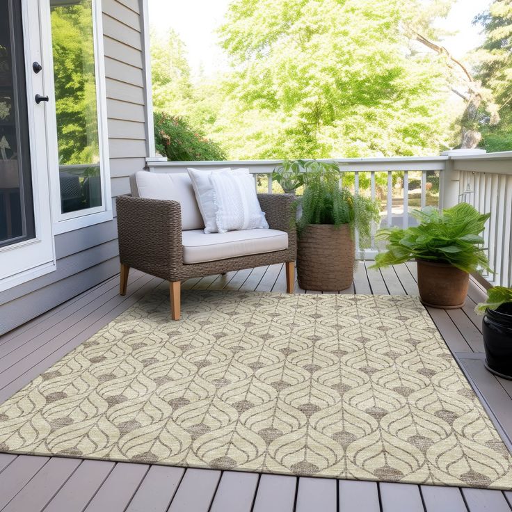 an outdoor area rug on a deck with chairs and potted plants next to it