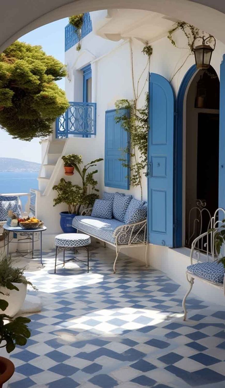 an outdoor patio with blue shutters and potted plants on either side of it