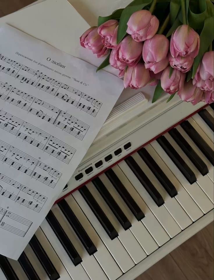 pink tulips and sheet music on piano keyboard