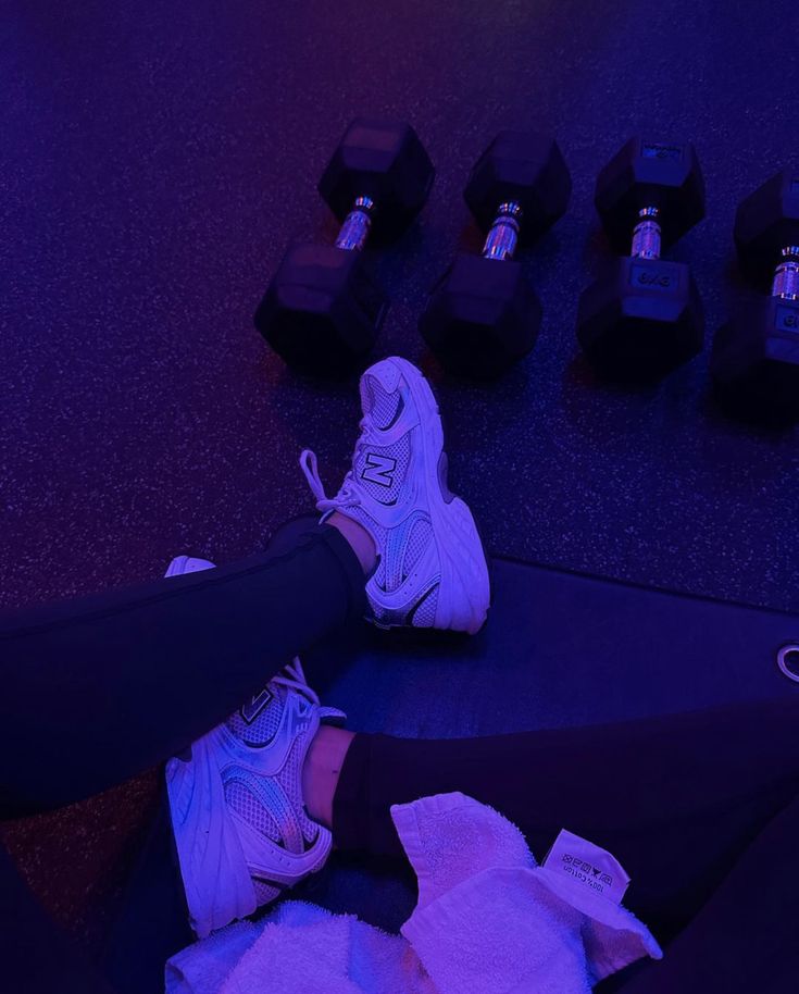 a person is sitting on the ground with their feet up in front of dumbbells