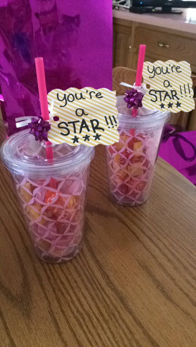 two plastic cups filled with candy sitting on top of a table next to a purple bag