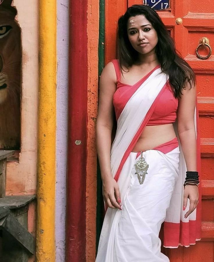 a woman in a red and white sari standing next to a lion statue on the side of a building