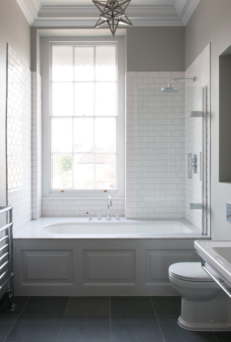 a white bath tub sitting under a window next to a toilet