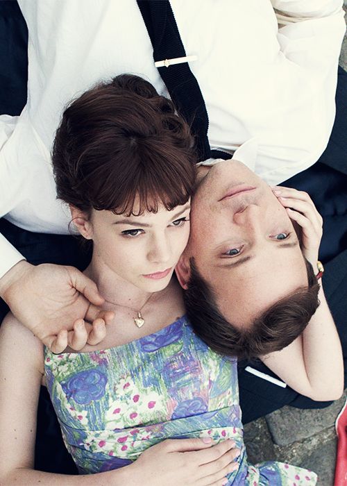 a man and woman laying on the ground next to each other with their heads together