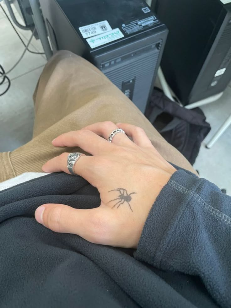 a woman's hand with a spider tattoo on her left wrist, sitting in front of a computer